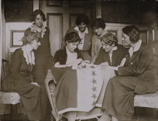 Alice Paul näht Sterne auf die Frauenwahlrechtsflagge, während andere Frauen zuschauen, um 1920